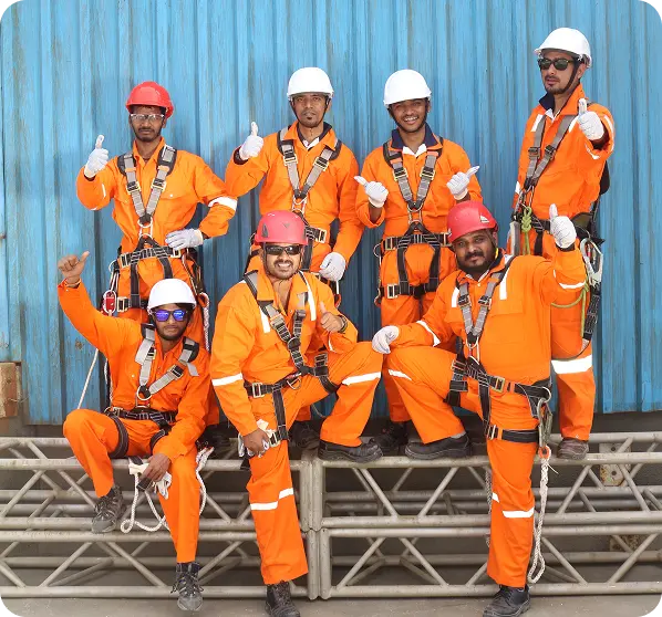 Contractor Safety Management - Group of workers in orange safety coveralls and hard hats posing with thumbs up